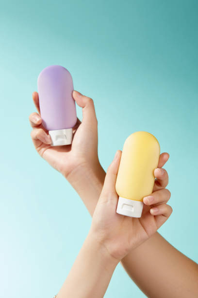 istock A bright turquoise backdrop features two hands holding a purple and a yellow lotion bottle. The contrast between the hues produces a sleek, eye-catching appearance that is ideal for product displays. 2177201305