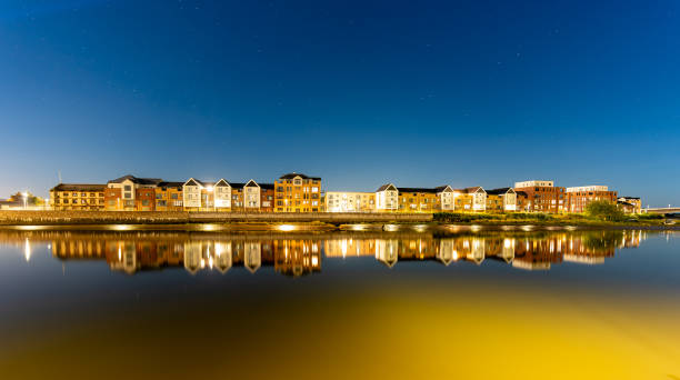 Townscape of Barnstaple by night, with contemporary houses mirrored in the River Taw