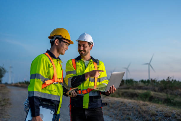 istock Diverse ethnicity male technicians working in the wind turbines field. Innovation engineer men use laptop computer work to develop environmental renewable clean energy outdoors at windmill power farm. 2177203825