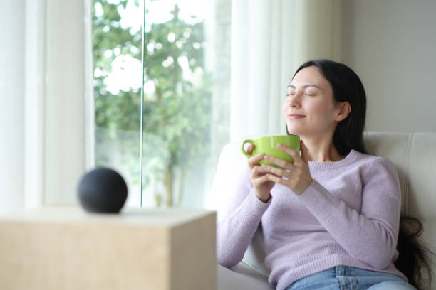istock Relaxed asian woman drinking coffee with smart speaker at home 2177206667