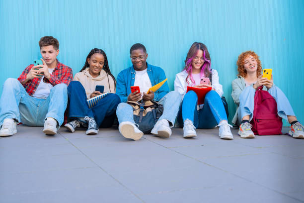 istock A group of diverse young people sitting outdoors using smartphones and notebooks 2177208419