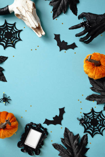 istock Halloween flat lay with pumpkins, cow skull, bats, photo frame, skeleton hand, and spider web on a blue background 2177218143