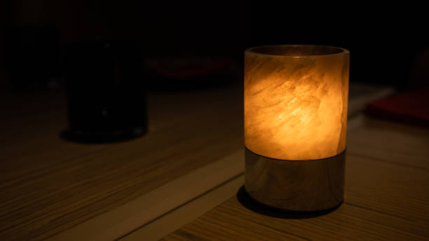 istock A candle inside glass is lit and illuminate on a wooden table inside restaurant at night. 2177218265