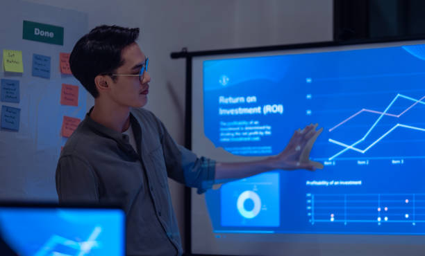 istock asian leader present  business presentation in a dimly lit office, analyzing financial charts and data projections on a screen 2177218862