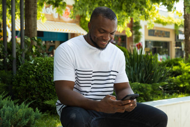 istock A young African-American man with a smartphone is sitting on a park bench 2177223243