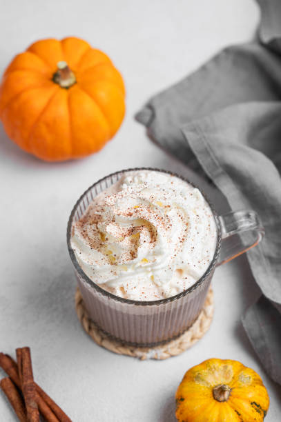 istock Spice latte or hot chocolate with whipped cream in glass cup on light background with decorative pumpkins and cinnamon stick 2177223262