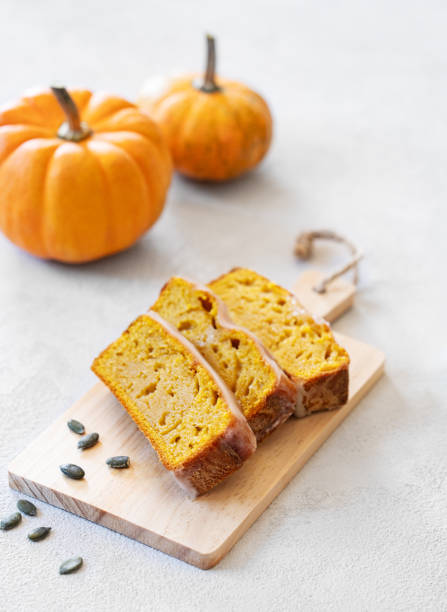 istock Pumpkin sweet bread or cake with icing on a wooden board on a light background with decorative pumpkins and seeds. 2177223287