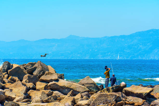 Woman spinning fishing in the sea with a rod, from the rocks