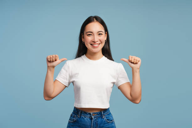 istock Young, smiling Asian woman pointing thumbs at herself, mockup, copy space 2177231603