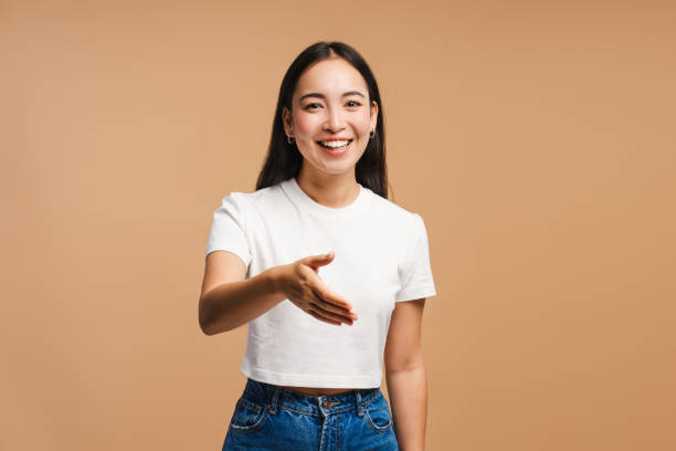 istock Young Asian woman smiling and extending hand for handshake on beige background 2177231649