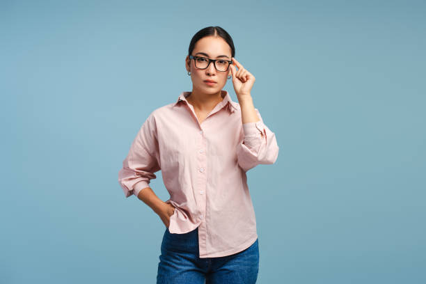 istock Confident, serious asian woman adjusting eyeglasses, looking at camera isolated on blue background 2177231734