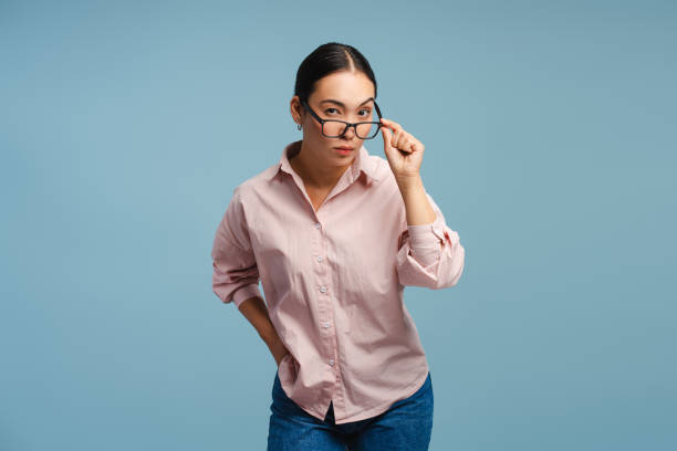 istock Serious, pensive Asian woman adjusting eyeglasses isolated on blue background 2177231749