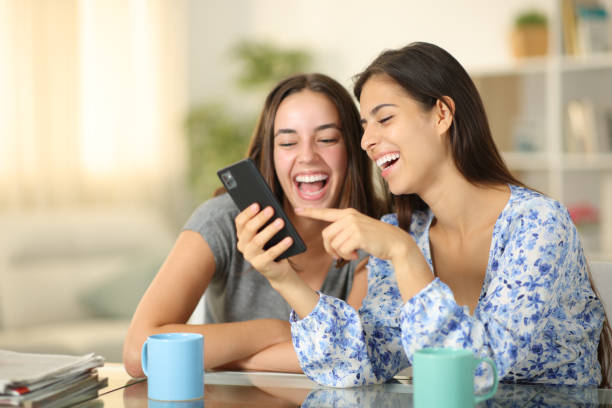 istock Two happy friends laughing checking smart phone at home 2177236411
