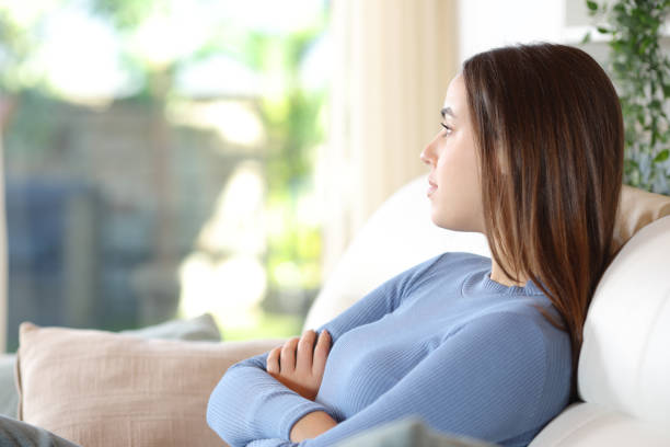 istock Serious woman with folded arms looking through a window at home 2177236714