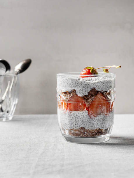Chia seed pudding. Chia pudding with strawberry in glass. Healthy dessert with chia seeds, strawberries, and granola. Strawberry Chia Pudding