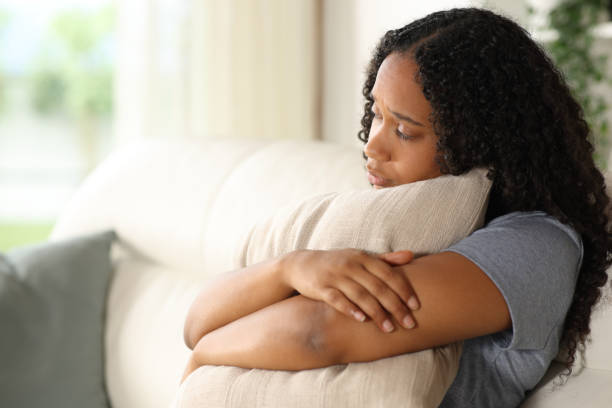 istock Black sad woman hugging pillow at home 2177236740