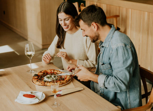 istock Couple enjoying a delightful meal at a cozy restaurant while sharing a delicious pizza and a glass of white wine 2177238877