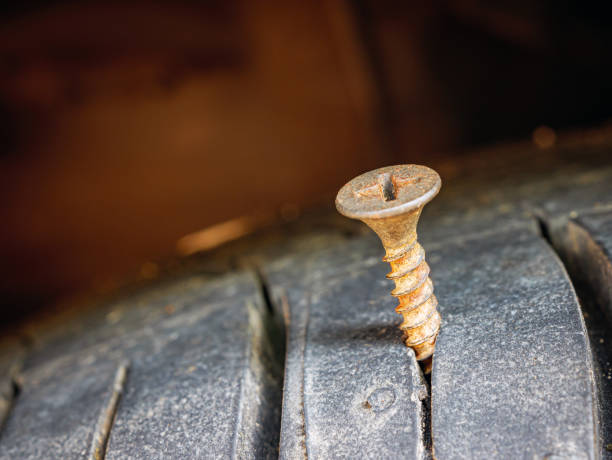 istock Close-up of a rusty screw driving into a car tire causing a puncture. 2177245495
