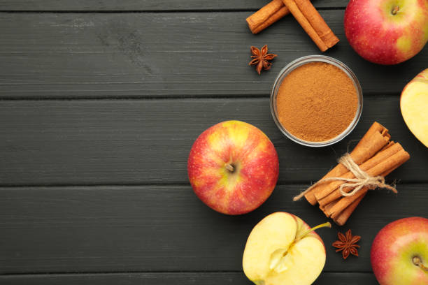 istock Red apple, cinnamon sticks and cinnamon in bowl on black wooden background. 2177247646