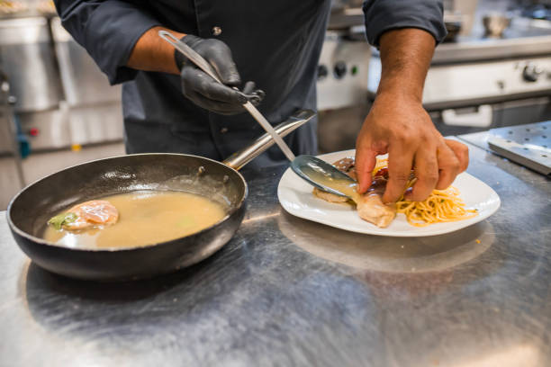 A chef skillfully prepares gourmet pasta with sauce in a professional kitchen setting. The meticulously plated dish showcases culinary expertise and attention to detail, creating a delicious and visually appealing meal.