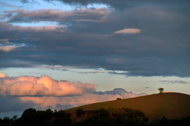 silhouette of hill against cloudy sky in warm sunset light