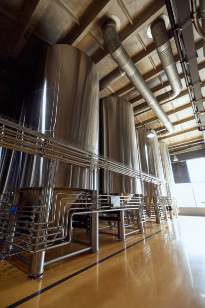 istock Large, modern brewery with several stainless steel fermentation tanks and pipes, connected by a network of pipes and valves. 2177261482