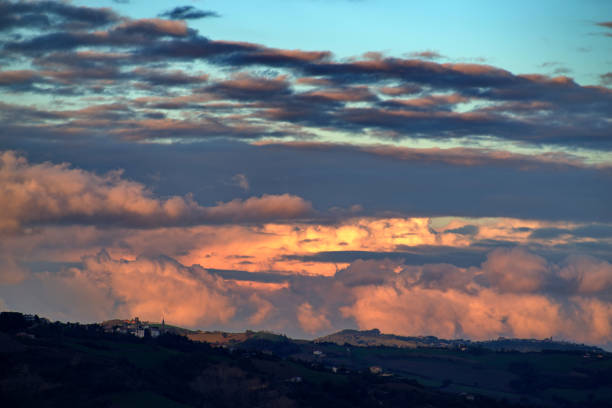 silhouette of hill against cloudy sky in warm sunset light