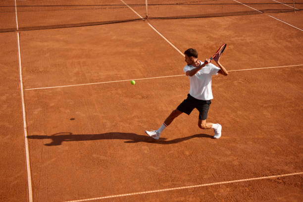 Dynamic image of athletic young man, tennis player in motion on court, playing, practicing, hitting ball with racket. Focus