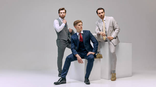 istock Young attractive men in classy suits, confidently standing together, exuding professionalism and readiness for business engagements against white background. 2177264806