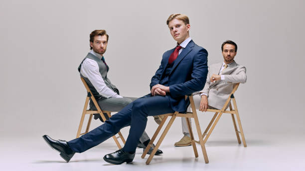 Group of young men sitting on chairs in relaxed pose. They exude confidence and composure while maintaining professional demeanor.
