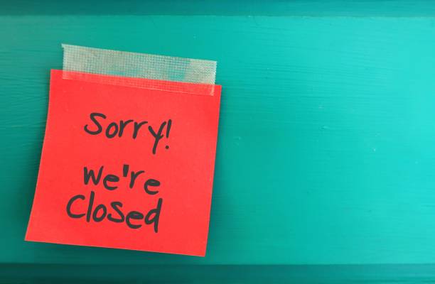 Red paper note with  text written SORRY WE'RE CLOSED on copy space green wall - to inform customers or visitors the place is not in service hours business, shop is closed temporary or permanently