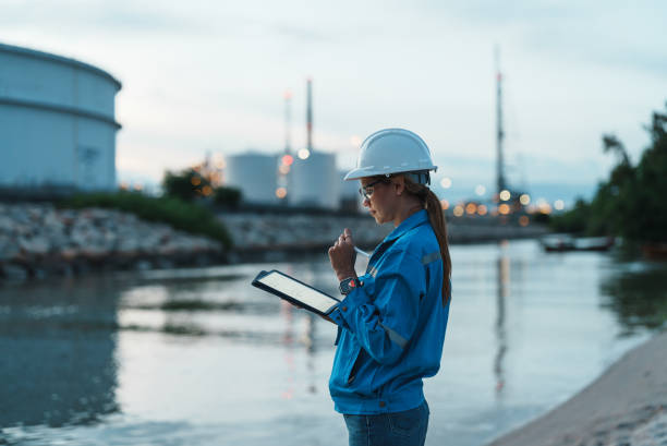 Female engineer works overtime at petroleum refinery.