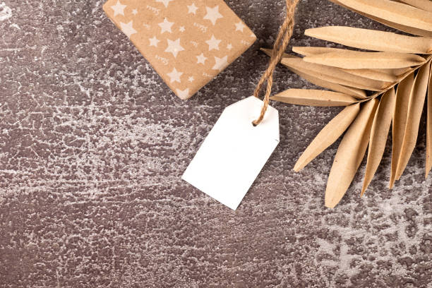 Empty white tag with gifts and Christmas decor on dark conkrete background. Christmas greeting card mockup.