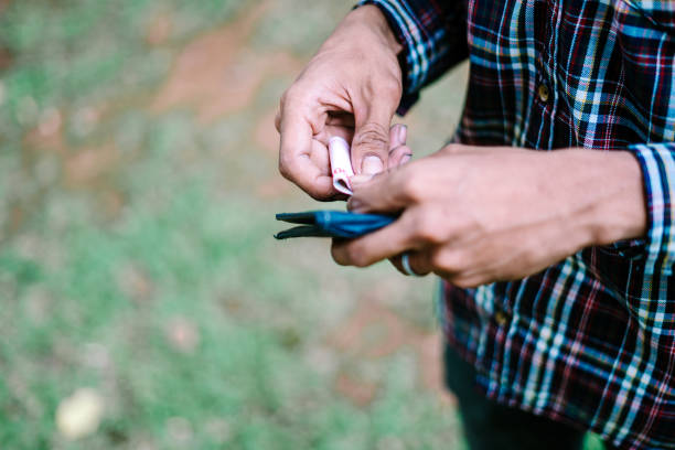 Southeast Asian man looking into his wallet, expressing concern or curiosity about finances. Perfect for projects focused on budgeting, personal finance, or everyday life.