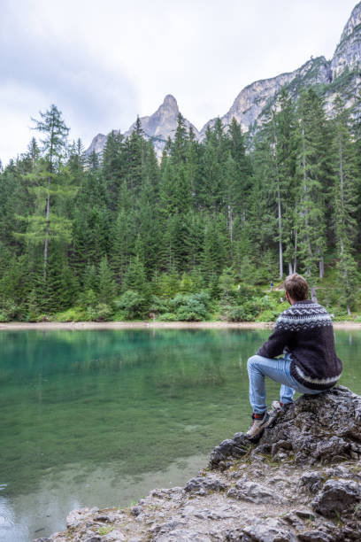 istock Man Sitting on Rock by Tranquil Mountain Lake 2177270935