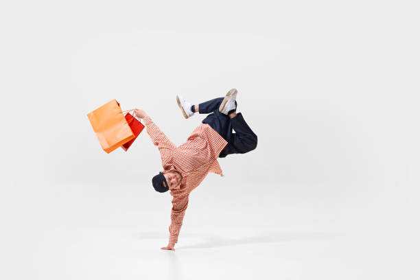 istock Dynamic image of young man in casual clothes standing on one hand in breakdance pose with colorful shopping bags 2177274281