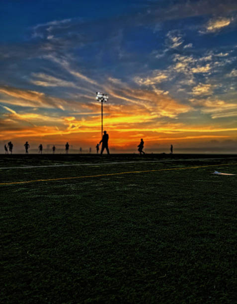 Sunrise over a beautful dark-green turf field. Yellow and blue sky.