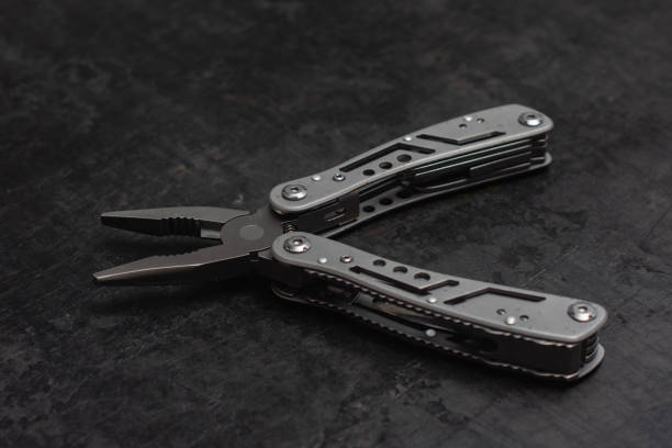 istock Tactical outdoor multi-tool with pliers, blade, screwdriver and other tools on a dark concrete background. Universal multitool for tourism and repair. 2177280872