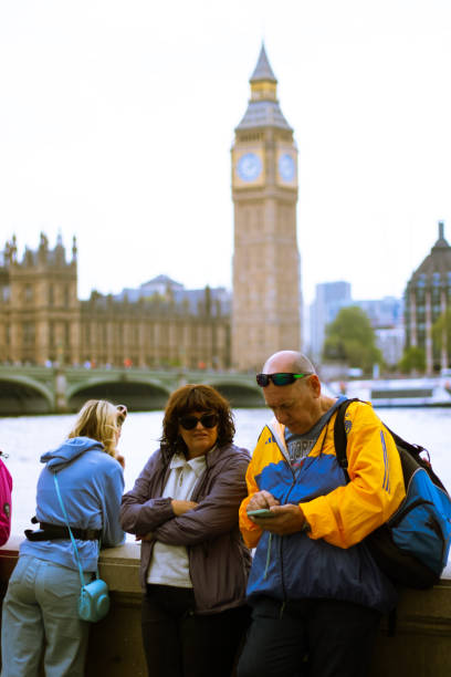 London, England, May 19 2023: Tourists looking to their phone by the Bib Ben during Autumn