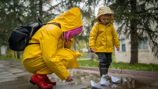 istock It's springtime. A small child in rubber boots jumps through puddles, plays and launches paper boats on the water. 2177283507