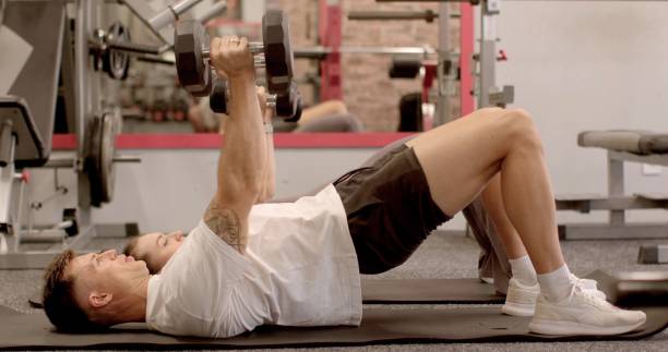 istock Man focused determined performing dumbbell chest press exercise gym 2177286836