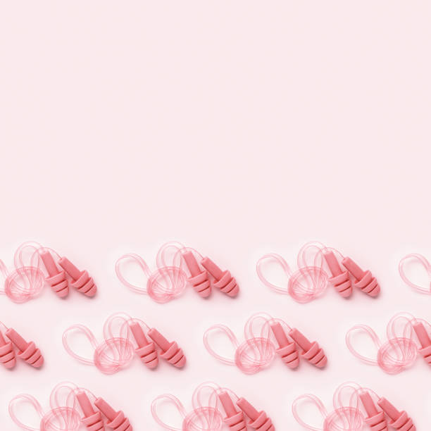 istock Reusable silicone pale pink color earplugs, for swim, sleep, rest as minimal trend pattern on pink background. Soft, flexible ear plug on cord against noise, protect hear, close up, top view 2177287427