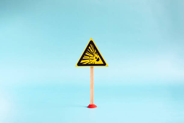 Yellow triangular sign with flying stones in close-up on a light background