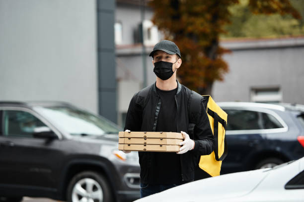 istock Delivery man carrying pizza boxes to a contemporary office building during work hours 2177289039