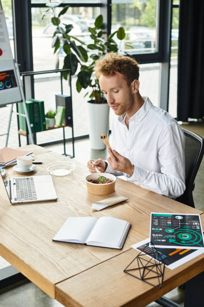 istock Focused redhead businessman in a modern office enjoying a meal while working on a project 2177290526