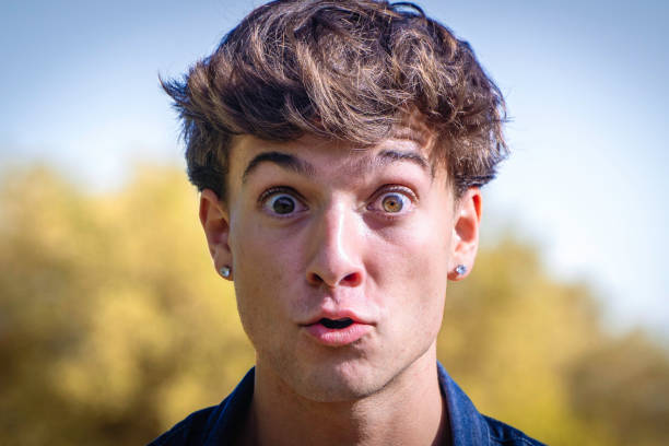 Close-up of a young man with a surprised expression. Outdoors