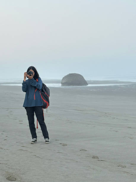istock Young woman takes photo on empty beach 2177294107