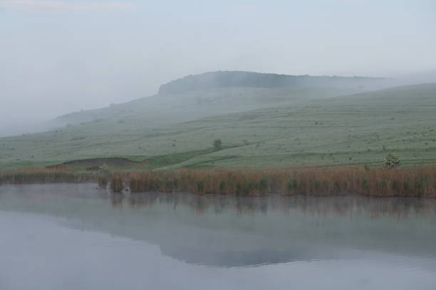 Foggy perspective over a lake. Still water lake mirroring the hills.