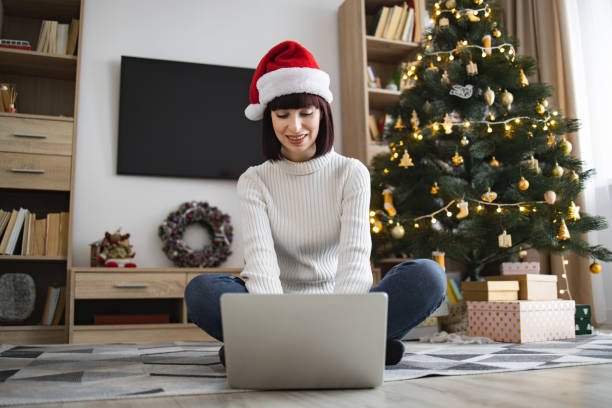 istock Woman in Santa hat using laptop near Christmas tree 2177298497
