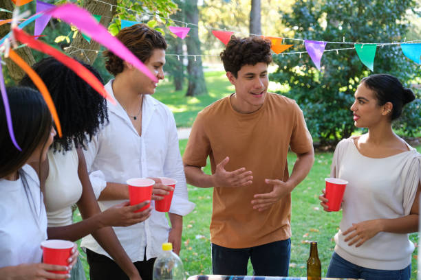 istock Diverse young adults having fun, chatting and drinking at a party outdoors 2177302218